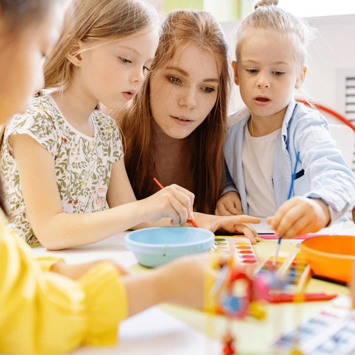 Erzieherin unterstützt Kinder bei einem Malangebot in der Kita